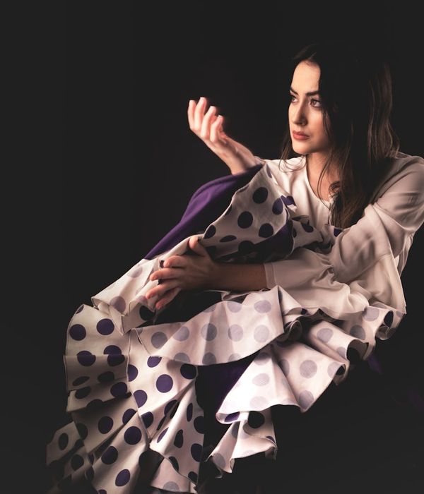 Woman in a calm, flowing movement pose in a dark room with mint green light accents.